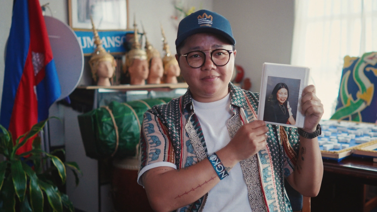 A person wearing a baseball cap is holding up a photo.