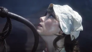 A person wearing a white hat has their chin resting on a whip